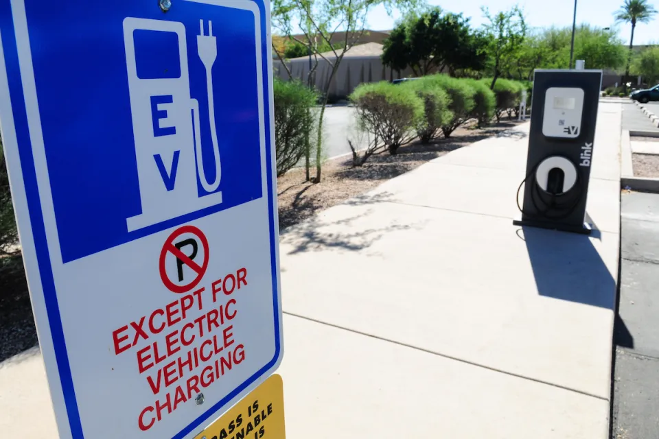 Close-up of EV charging station sign with "No Parking except for EV charging" in outdoor parking lot.